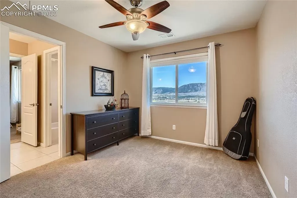 A bedroom with a ceiling fan and a large window