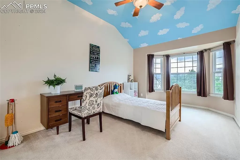 A bedroom with a bed , desk , chair and ceiling fan.