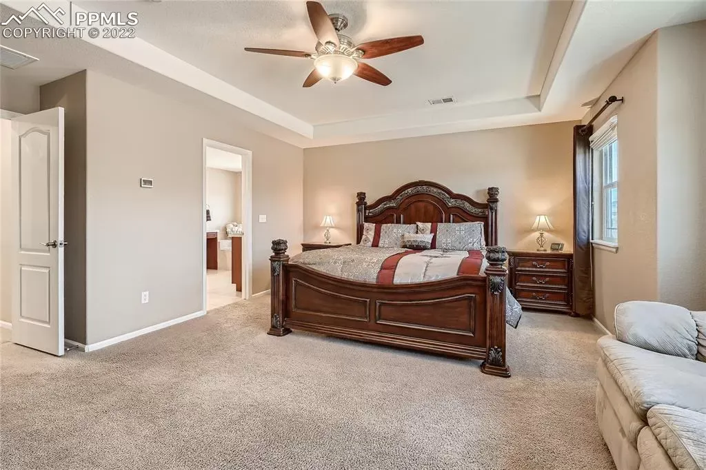 A bedroom with a large bed and a ceiling fan