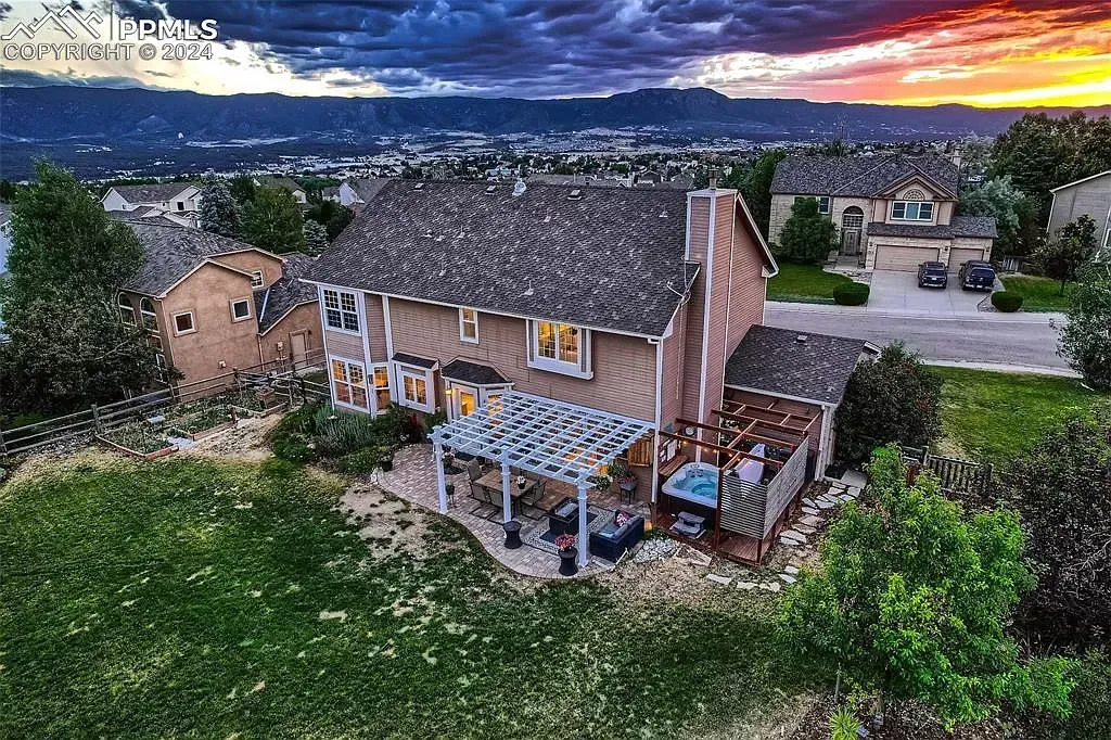 An aerial view of a house with a pergola on the backyard at sunset.