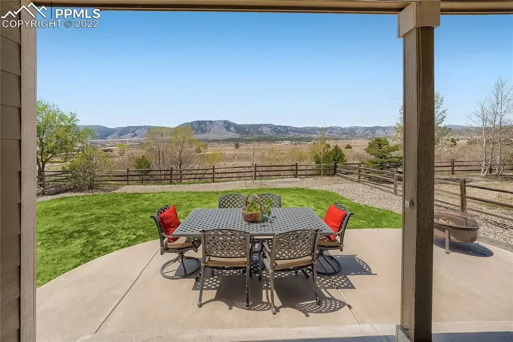 There is a table and chairs on the patio with a view of the mountains.