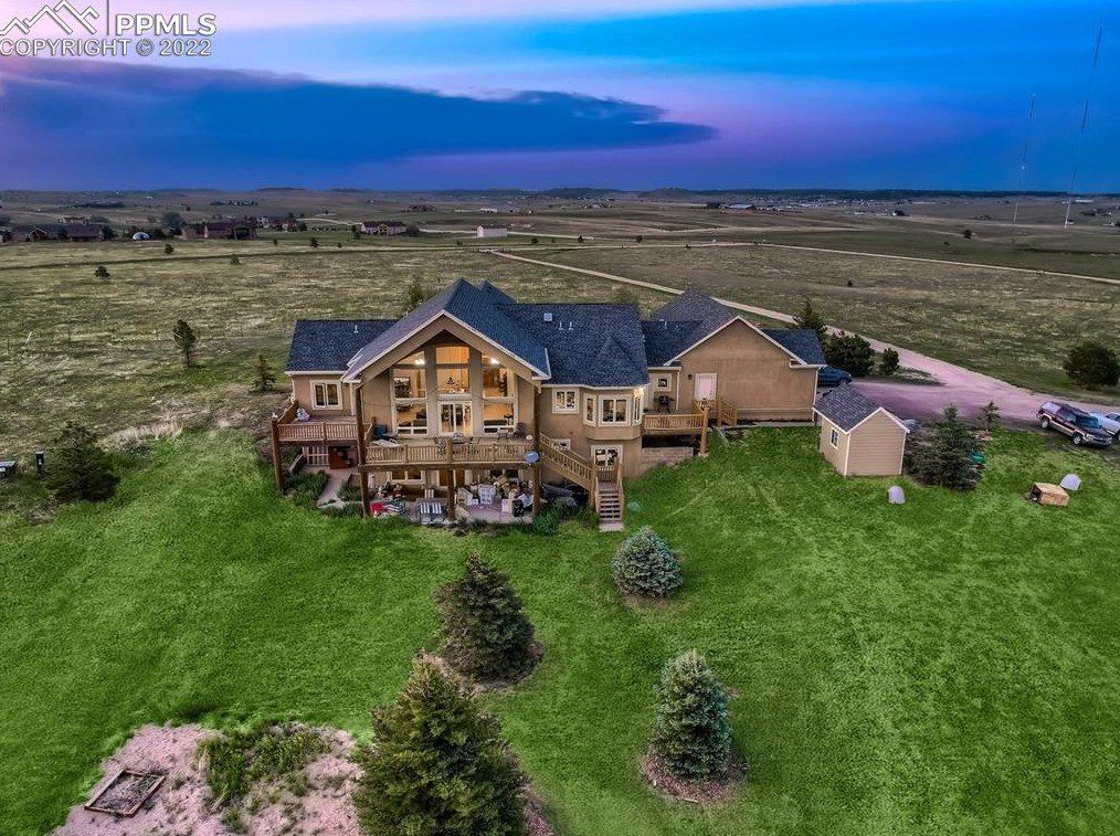 An aerial view of a large house in the middle of a lush green field.