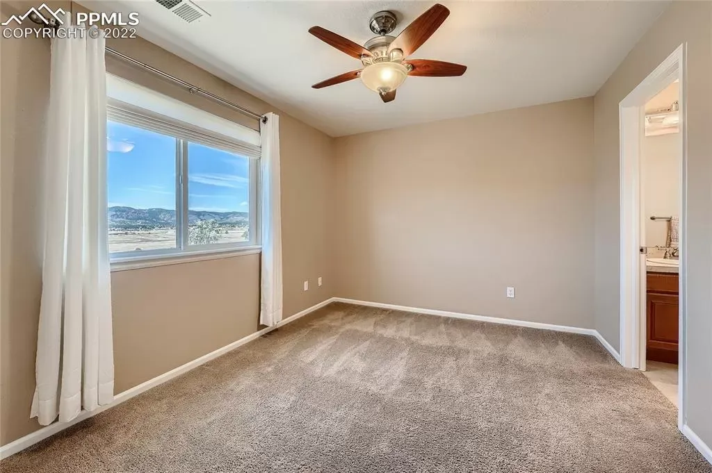 A bedroom with a ceiling fan and a large window.