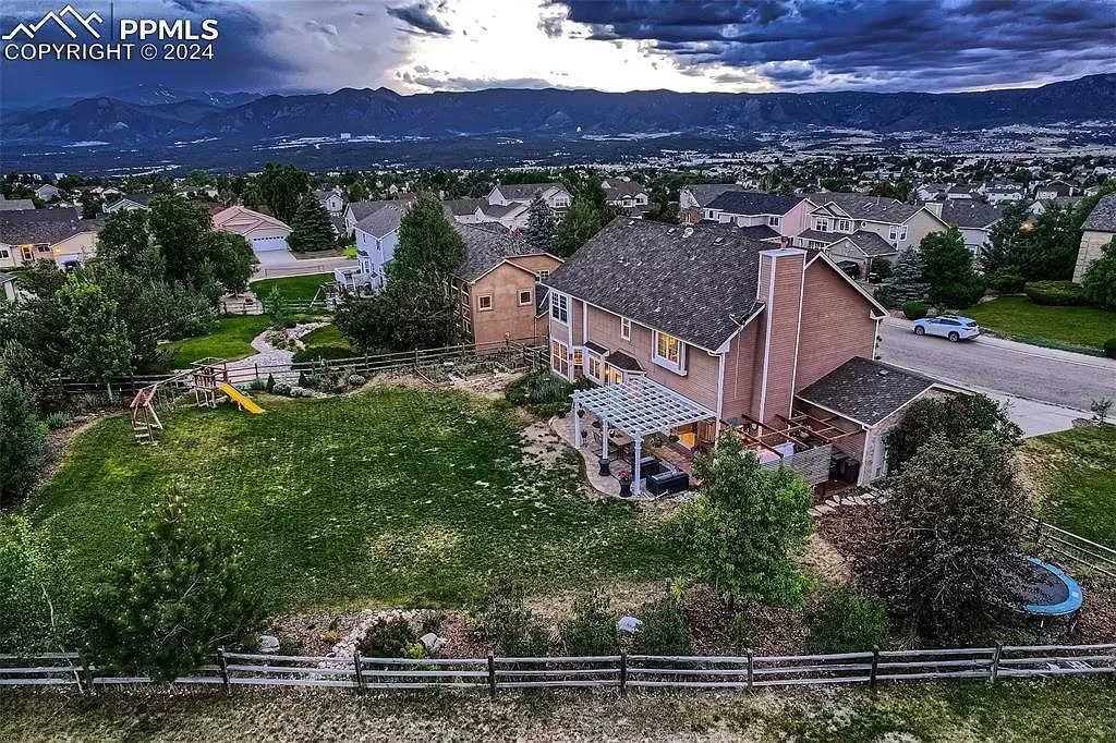 An aerial view of a large house surrounded by trees and a fence.