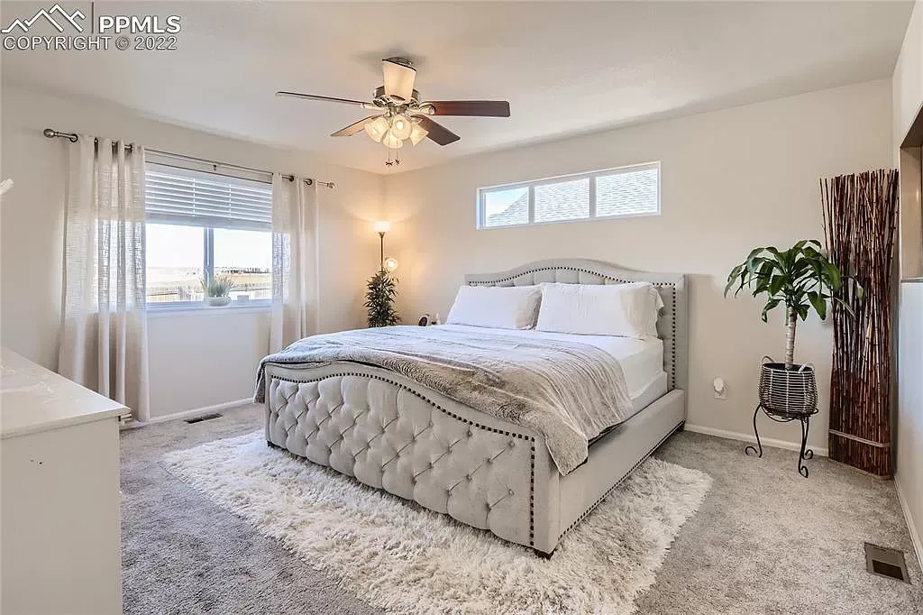 A bedroom with a large bed and a ceiling fan.