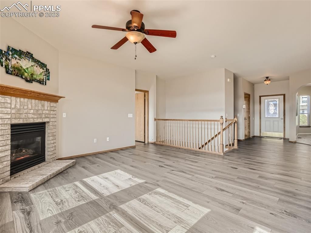 A living room with a fireplace and a ceiling fan