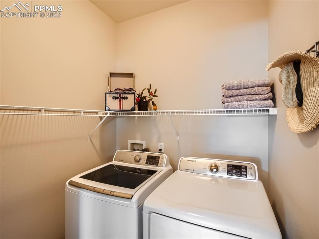 A laundry room with a washer and dryer and a hat hanging on the wall.