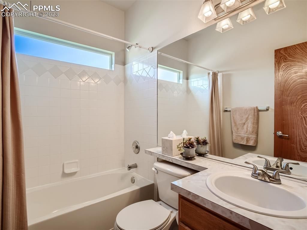 A bathroom with a toilet , sink , tub and mirror.