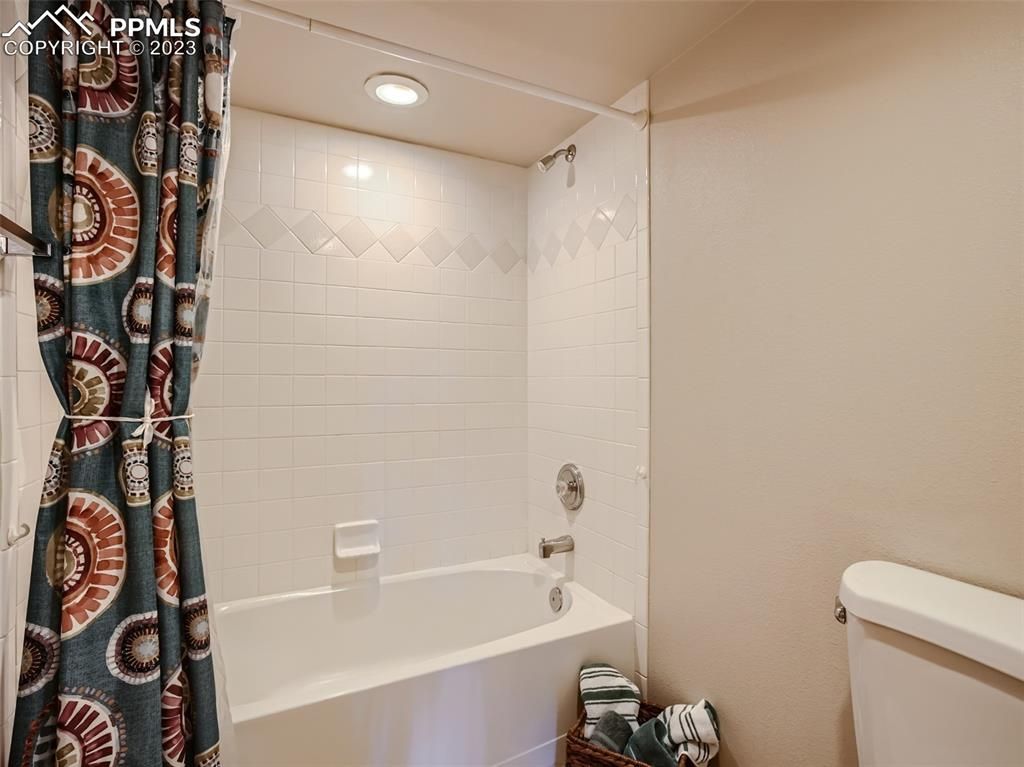 A bathroom with a bathtub , toilet and shower curtain.