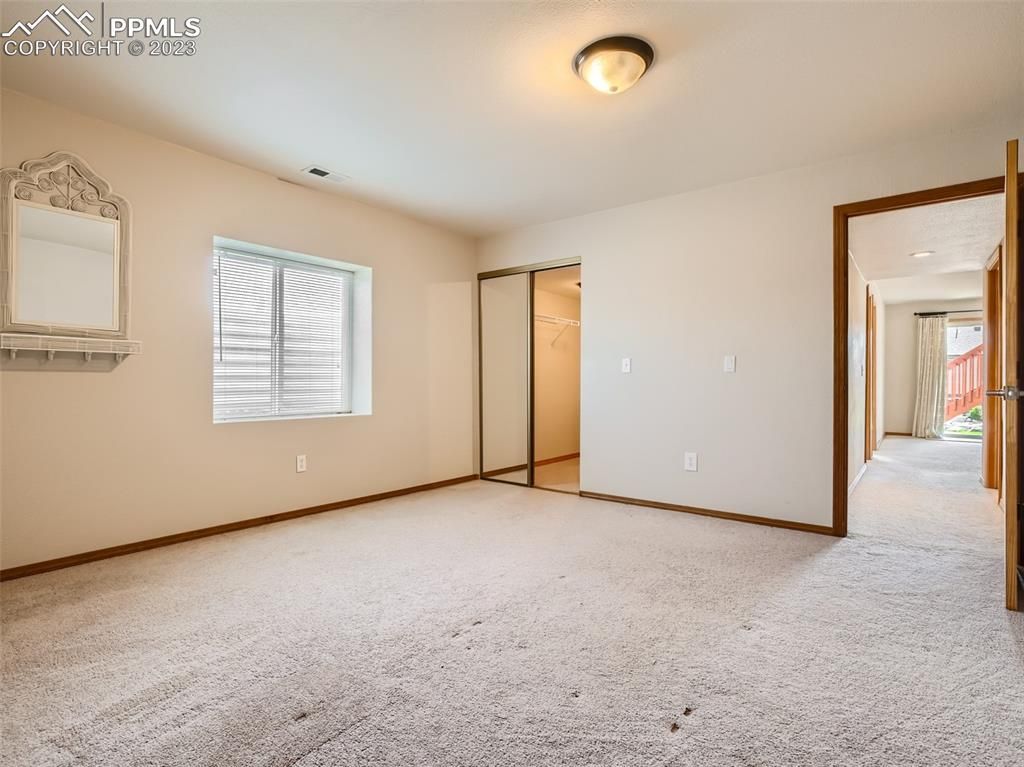 An empty bedroom with a mirror and a window