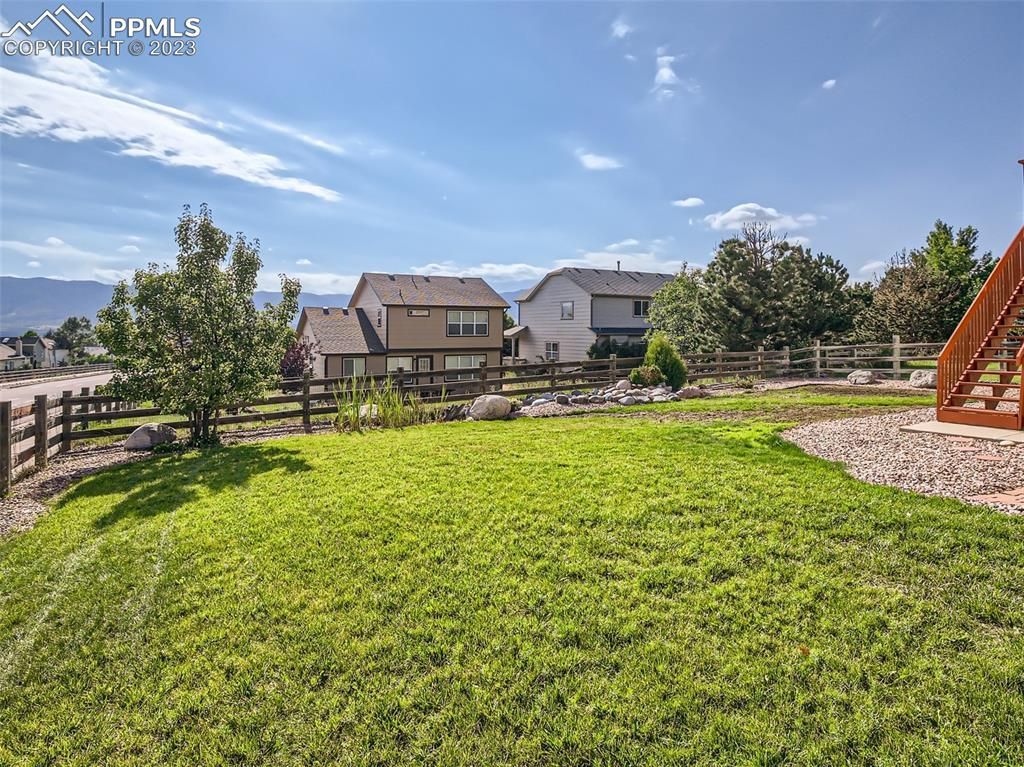 A large lush green yard with a fence and houses in the background.
