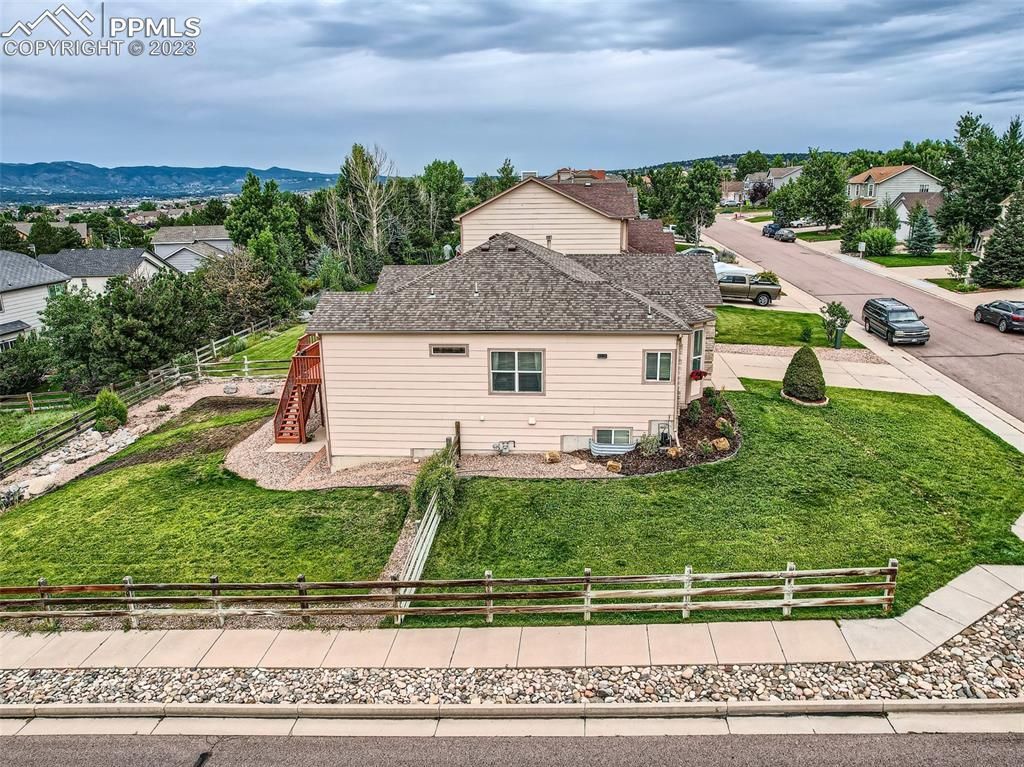 An aerial view of a house with a fence in front of it in a residential area.