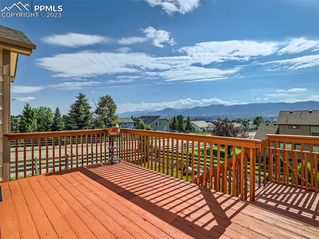 A large wooden deck with a railing and a view of the mountains.