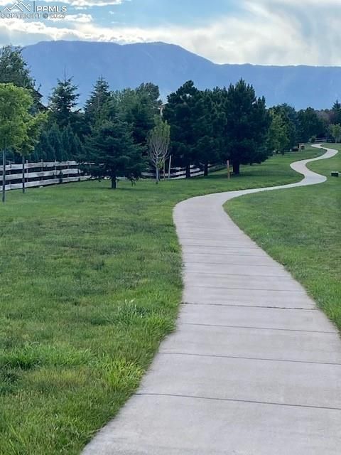 A path going through a grassy field with mountains in the background