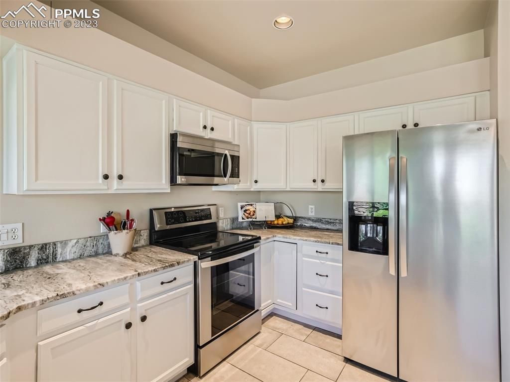 A kitchen with white cabinets , stainless steel appliances and granite counter tops.