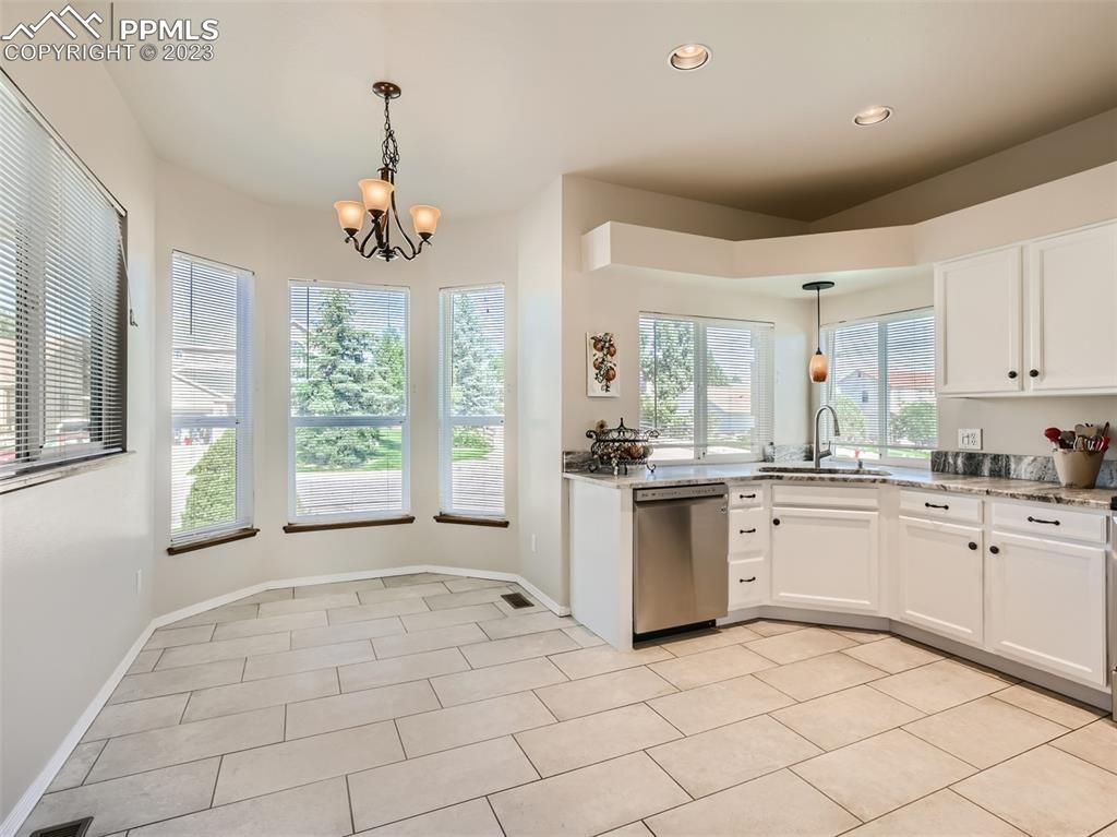 A kitchen with white cabinets , stainless steel appliances , and a tile floor.