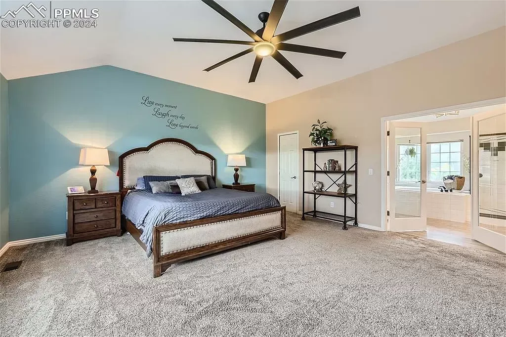 A bedroom with a large bed and a ceiling fan