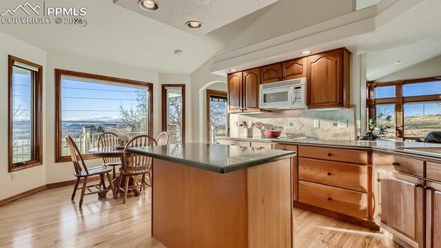 A kitchen with wooden cabinets , granite counter tops , and a large island.