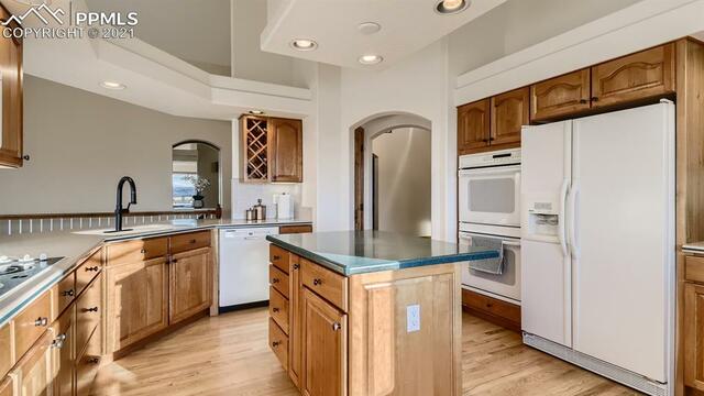 A kitchen with wooden cabinets , white appliances and a large island.