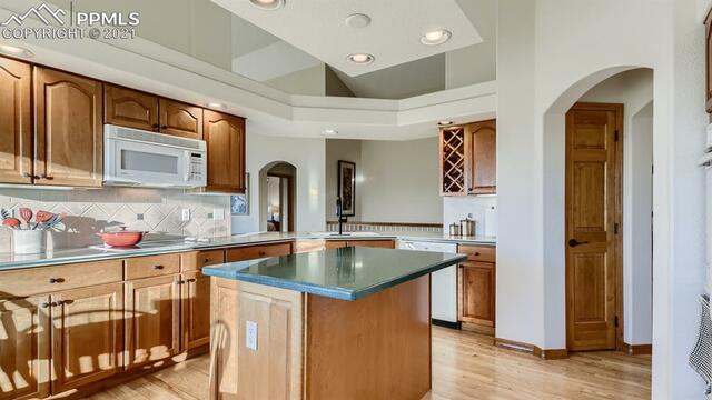 A kitchen with wooden cabinets , granite counter tops , and a large island.