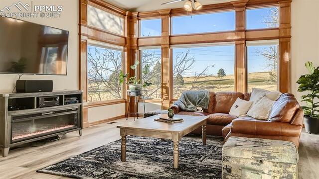 A living room with a couch , coffee table , television and lots of windows.
