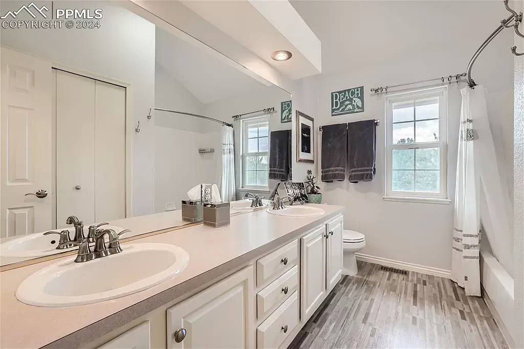 A bathroom with two sinks , a toilet , and a large mirror.
