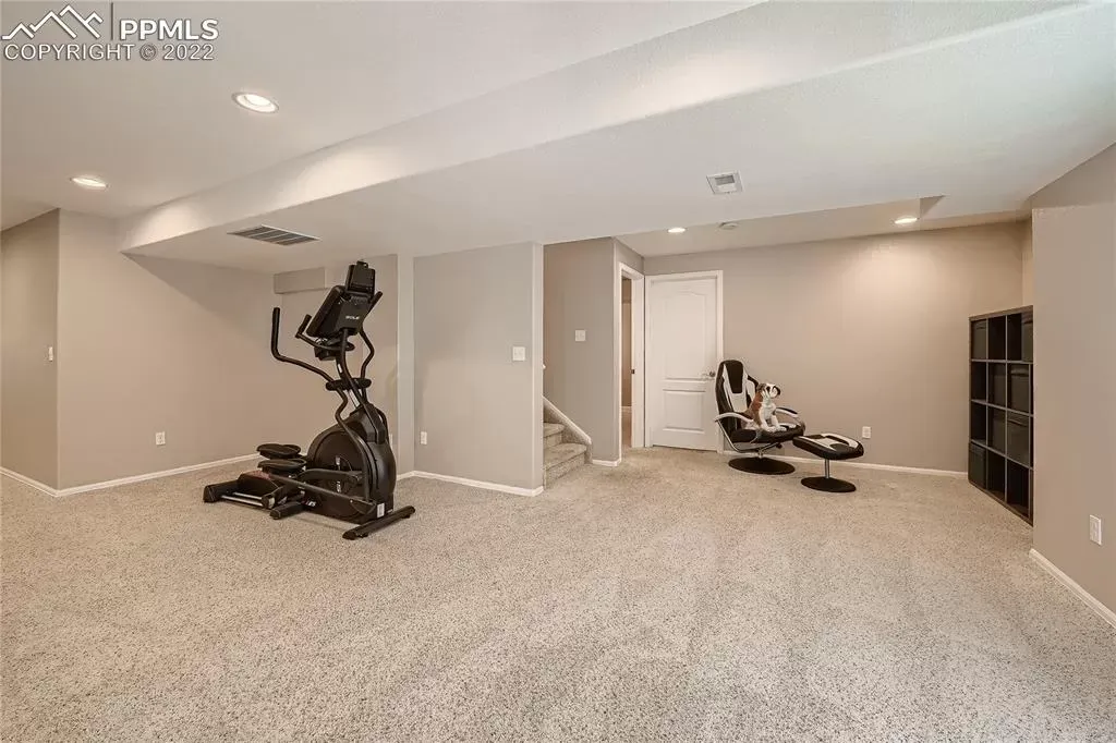 A basement with a exercise bike and a chair.