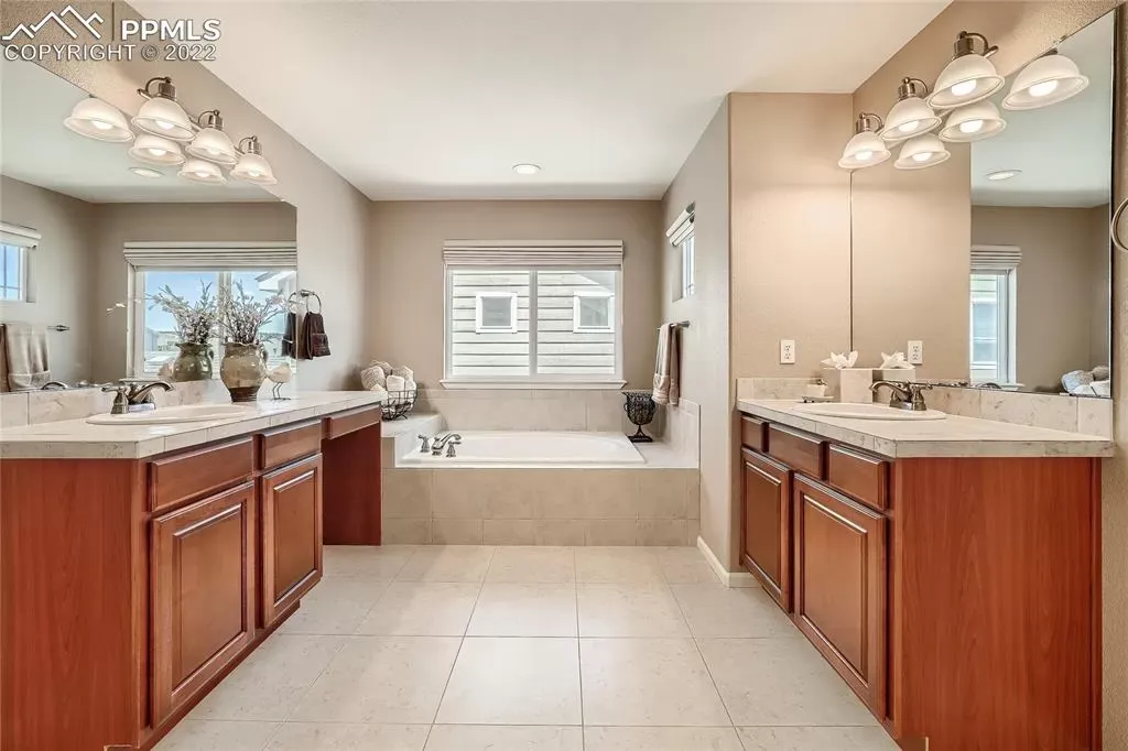 A bathroom with two sinks , a tub and two mirrors.