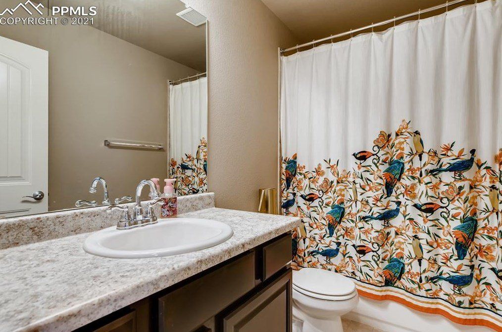 A bathroom with a sink , toilet , shower curtain and mirror.