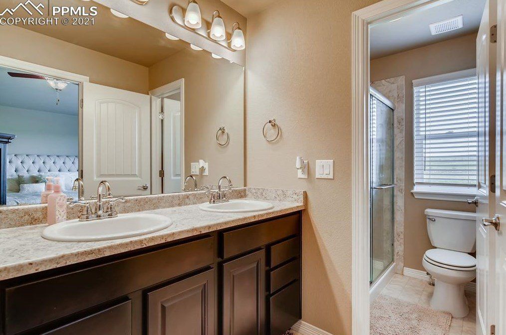 A bathroom with two sinks , a toilet and a mirror.