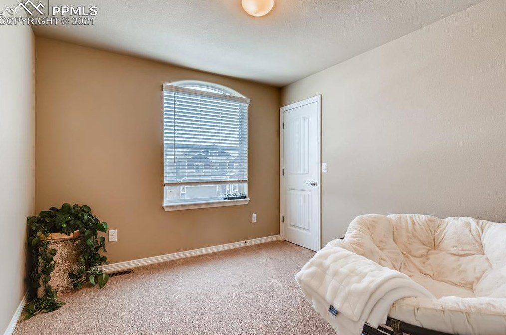 A bedroom with a couch and a window.