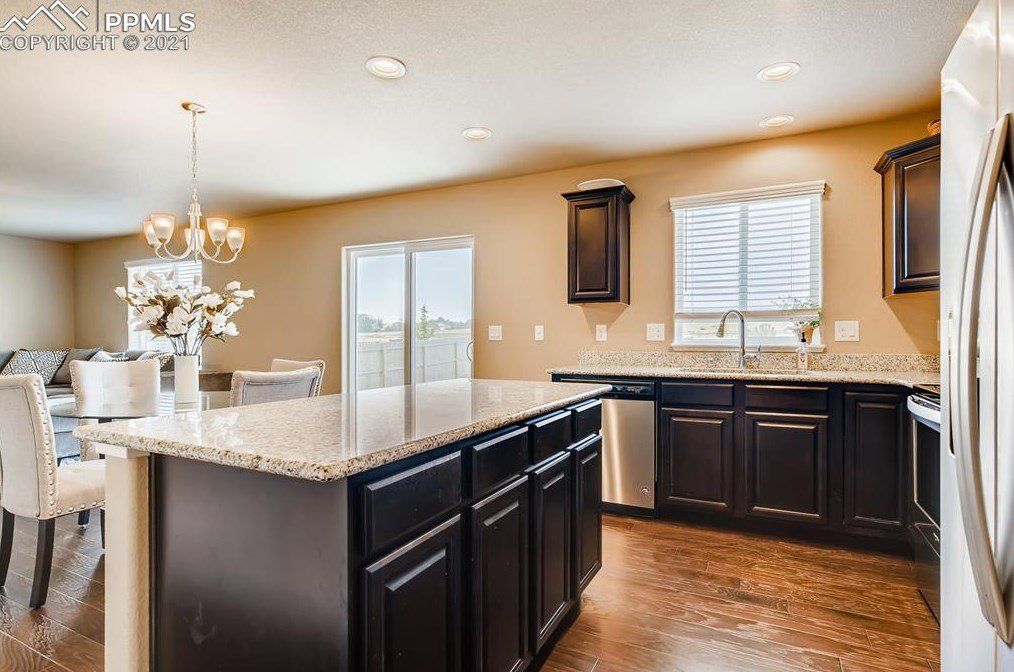 A kitchen with black cabinets , granite counter tops , stainless steel appliances and a large island.