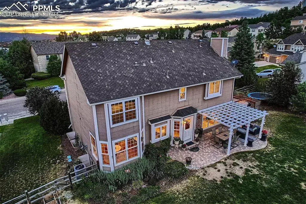 An aerial view of a house with a pergola in the backyard at sunset.