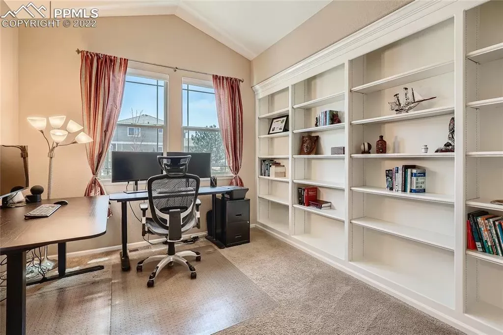 A home office with a desk , chair , computer and shelves.
