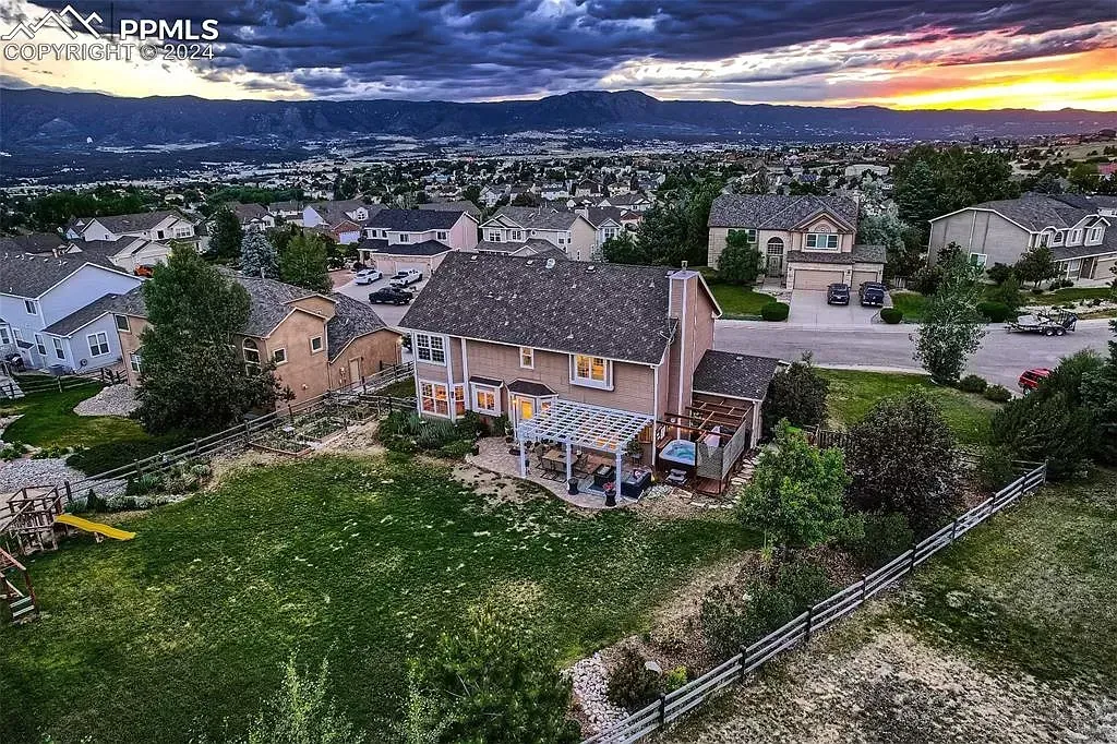 An aerial view of a house on a hill with a city in the background.