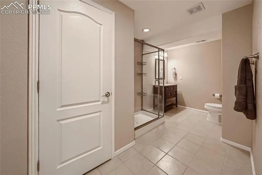 A bathroom with a toilet , sink , shower and mirror.
