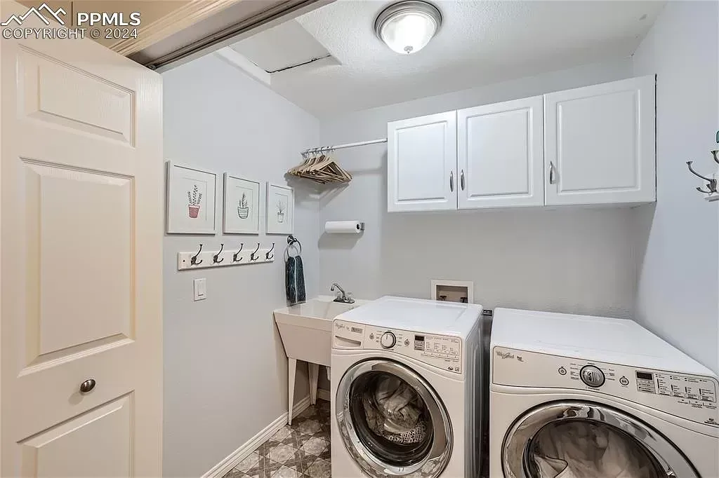 A laundry room with a washer and dryer and white cabinets.