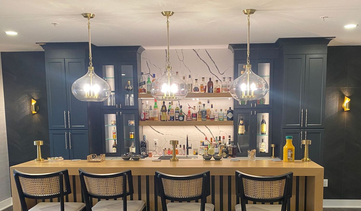 A bar with a lot of bottles on the shelves and chairs.