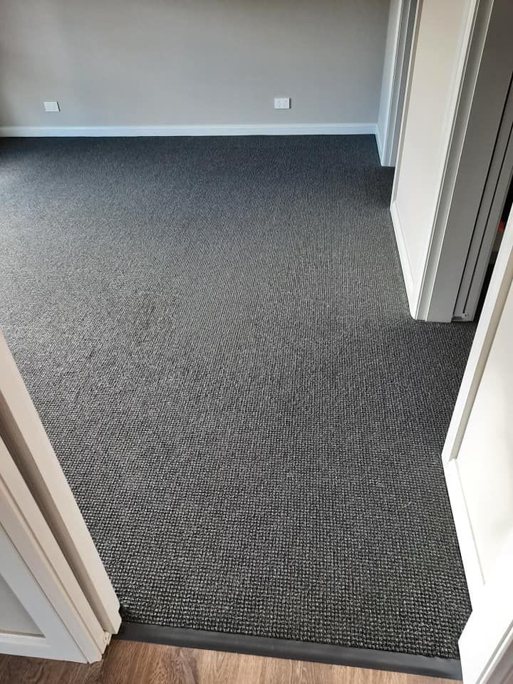 A room with a gray carpet and a wooden floor