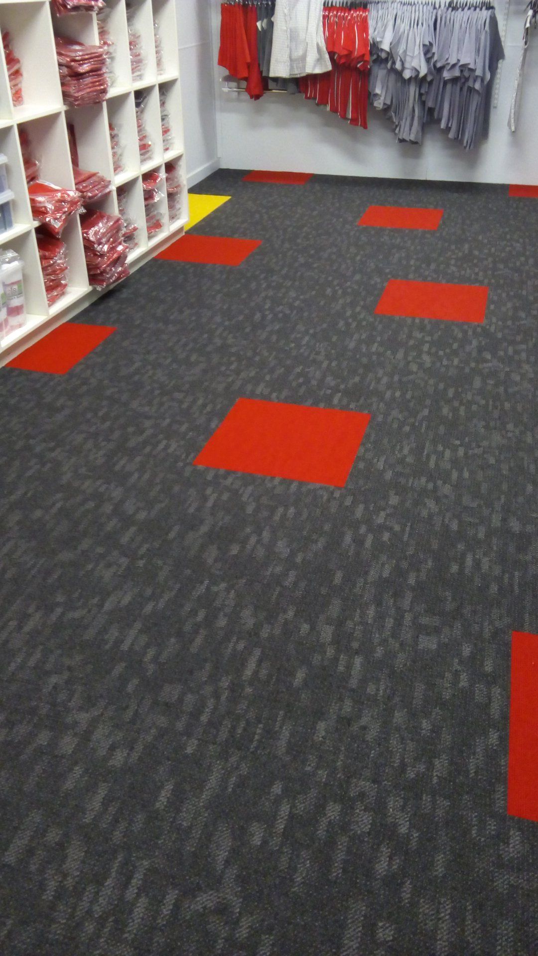 A room with a gray carpet and red squares on the floor