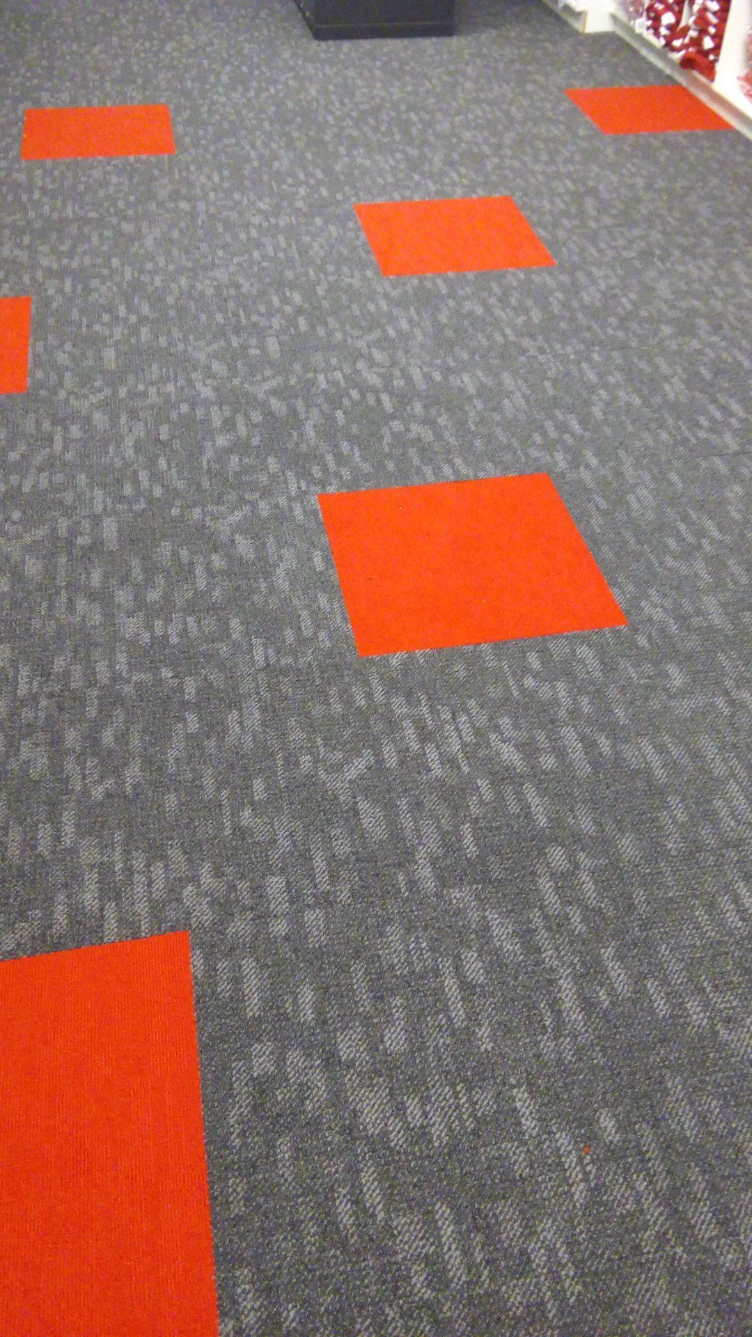 A gray carpet with orange squares on it in a room