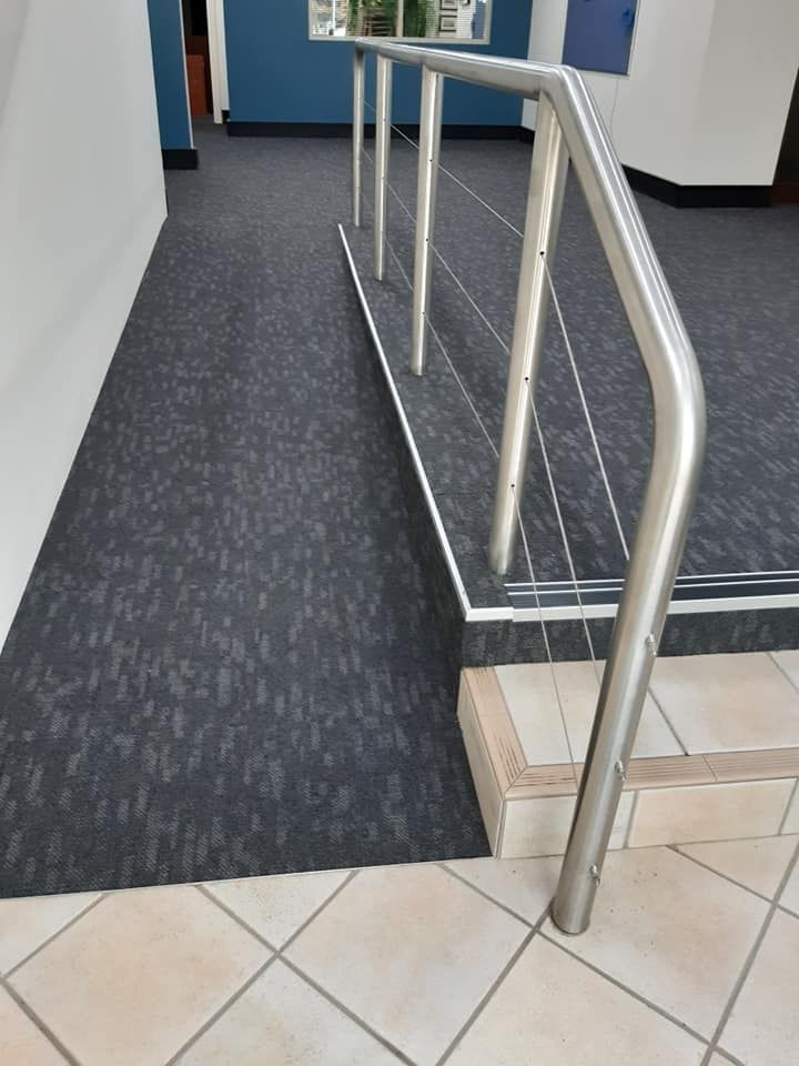 A staircase with a metal railing and a black carpet