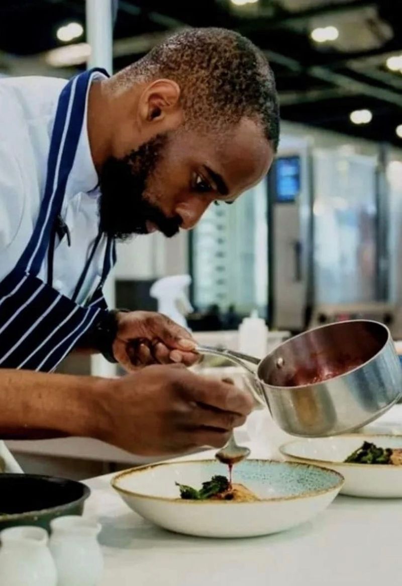 Chef David Henderson plating a dish with sauce