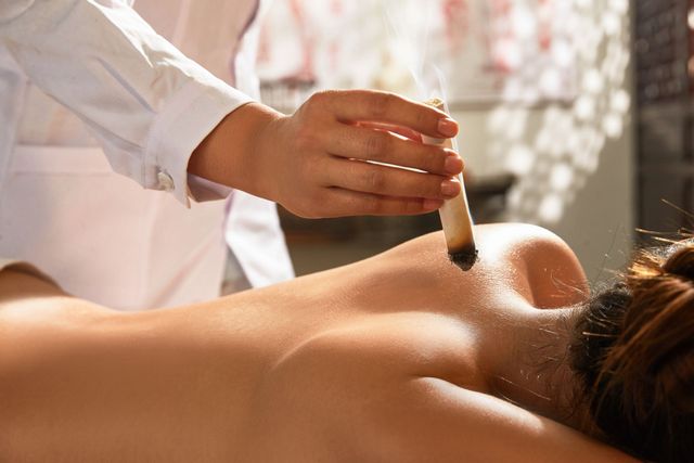 Una terapeuta de spa aplica aceite en la espalda desnuda de un cliente durante un masaje.