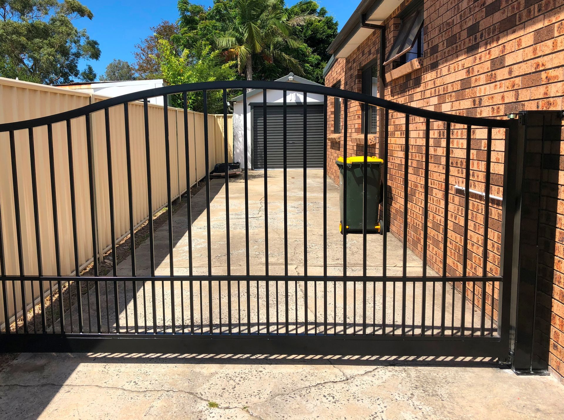 A black gate is open in front of a brick building