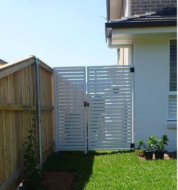 A white fence with a wooden fence behind it