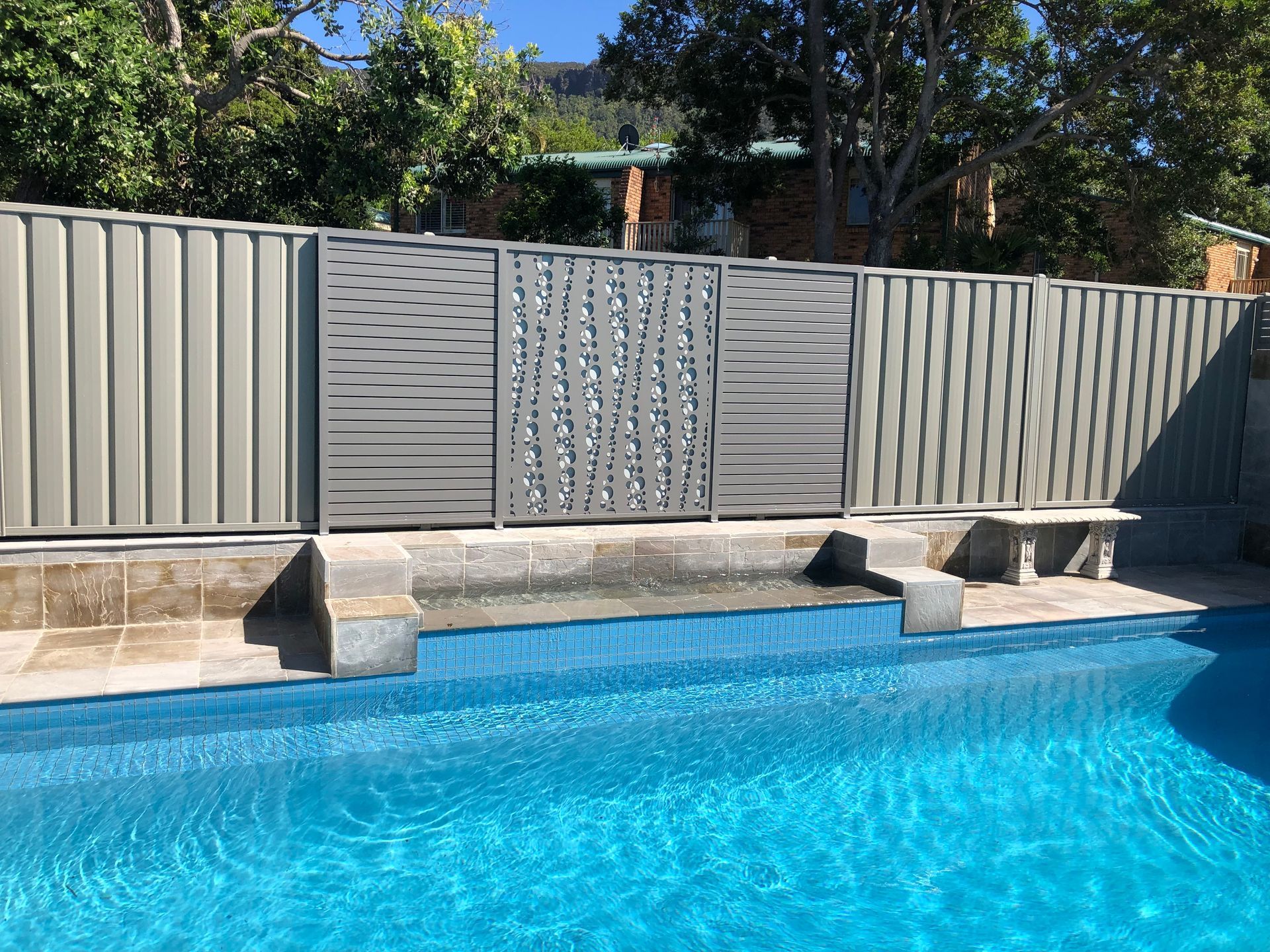 A fence surrounds a large swimming pool.