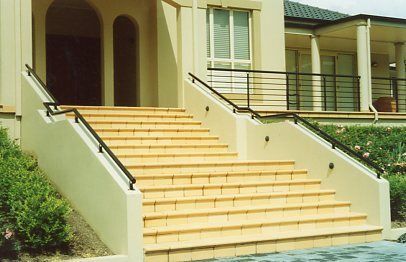 A set of stairs leading up to a house with a black railing