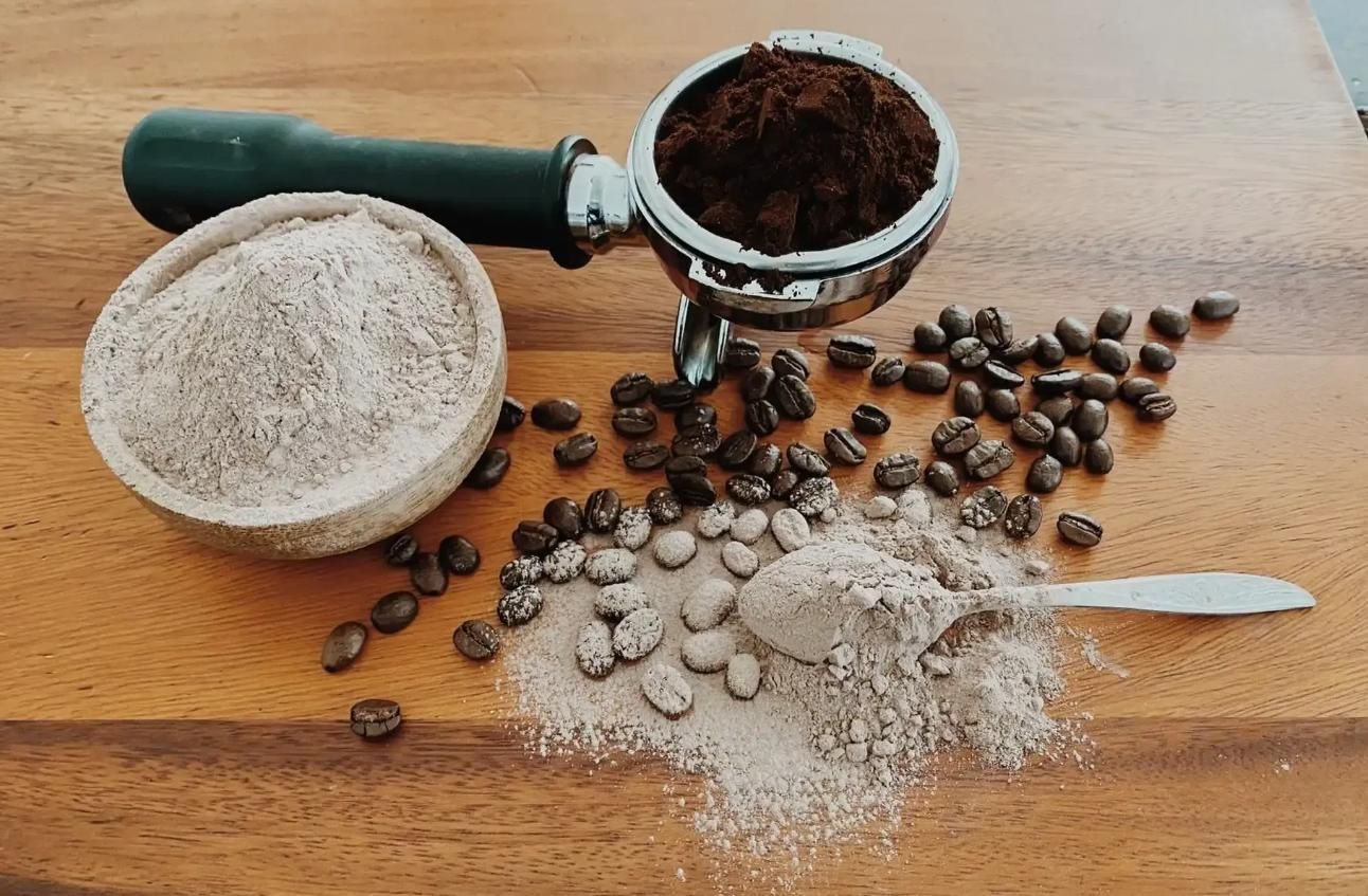 Coffee ingredients: ground coffee in a portafilter and bowl, beans, and powder on a wooden surface — Labroco Gourmet Coffee Supplier In Forster, NSW