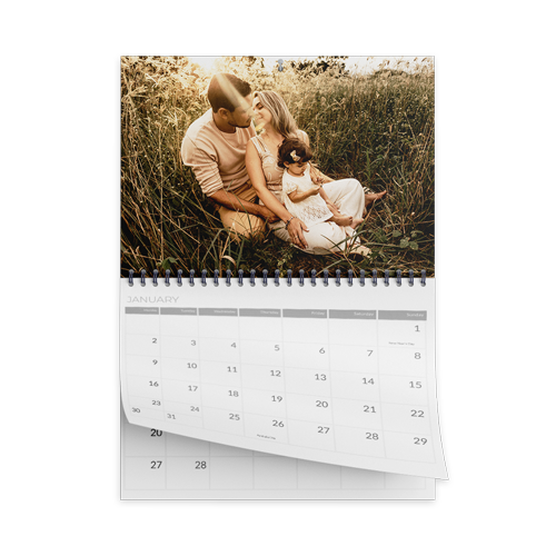 a calendar with a picture of a family sitting in the grass .